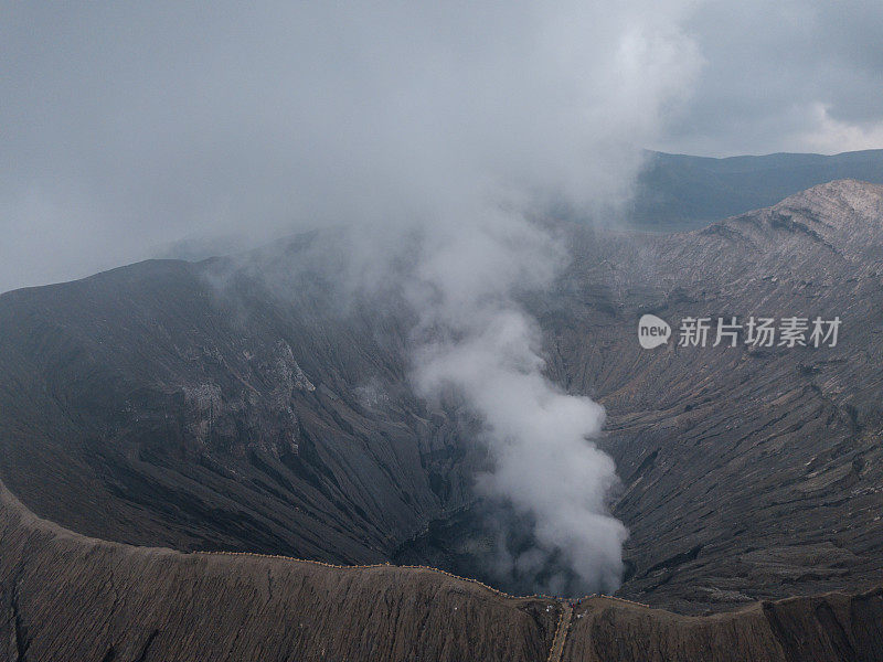 无人机鸟瞰图的Bromo火山口边缘与蒸汽在Bromo山国家公园在Cemoro Lawang村-东爪哇，印度尼西亚，亚洲。旅游目的地冒险的自然概念
